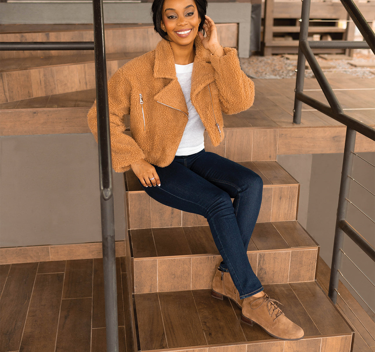 MUNRO ANTONIA ANKLE BOOTIE IN FAWN COLOR SUEDE ON MODEL WEARING BLUE JEANS AND TAN FLEESE SHORT JACKET SITTING ON STAIRS-LIFESTYLE