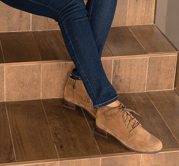 MUNRO ANTONIA ANKLE BOOTIE IN FAWN COLOR SUEDE ON MODEL WEARING BLUE JEANS SITTING ON STAIRS-LIFESTYLE