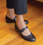 MUNRO BLACK LEATHER MJ MARY-JANE STEP-IN FLAT WITH STRAP ON MODEL WEARING LIGHT BLACK SLACKS-LIFESTYLE